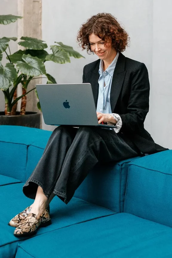 Personal Branding Business-Portrait einer Frau in formeller Kleidung: Sie trägt einen dunkelblauen Blazer und ein weißes Hemd, schaut freundlich in die Kamera und sitzt vor einem neutralen, grauen Hintergrund. Personal Branding Business-Portrait einer Frau in formeller Kleidung: Sie trägt einen dunkelblauen Blazer und ein weißes Hemd, schaut freundlich in die Kamera und sitzt vor einem neutralen, grauen Hintergrund.